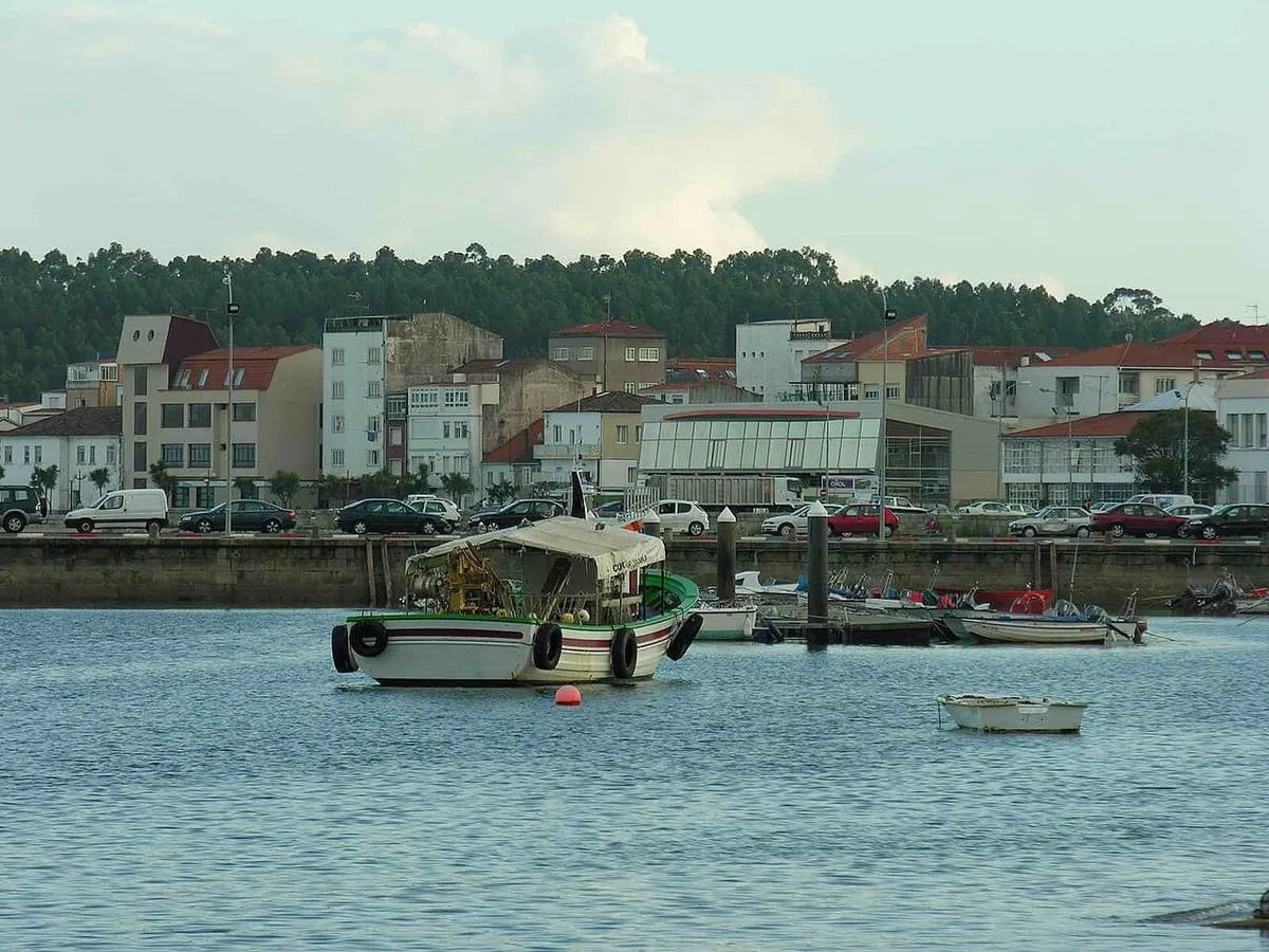 Barca fondeada frente a las casas y el paseo de A Pobra do Caramiñal