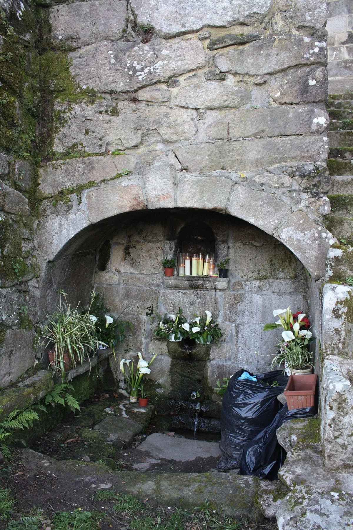 Hornacina de piedra con una imagen de la Virgen, velas y flores, en la capilla de la Virxe da Renda