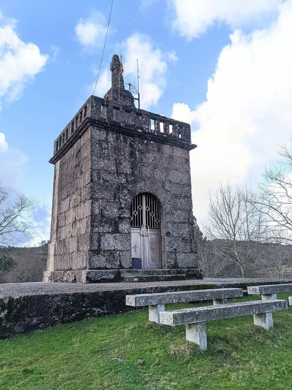 La capilla de Cristo Rei vista desde abajo, con cielo y árboles desnudos al fondo