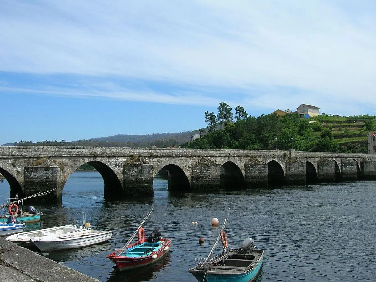 Puente medieval de arcos de piedra sobre el Verdugo en Ponte Sampaio, con barcas amarradas junto a la orilla
