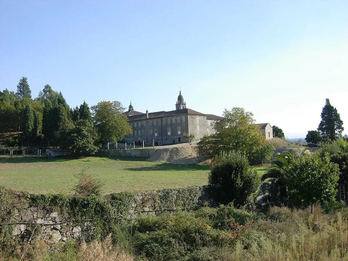El convento de Canedo visto de lejos entre árboles y prados