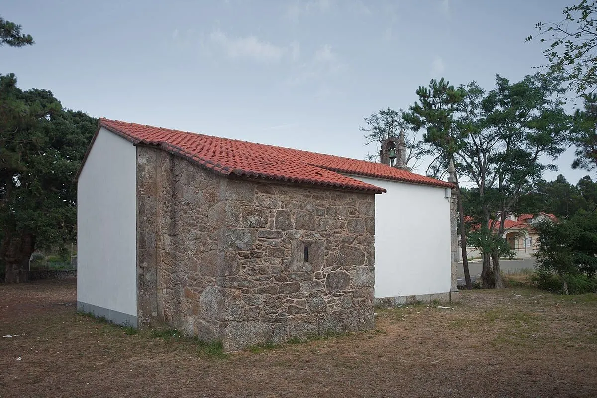 Lateral de la capilla de las Pardiñas con muros de piedra y tejado rojo