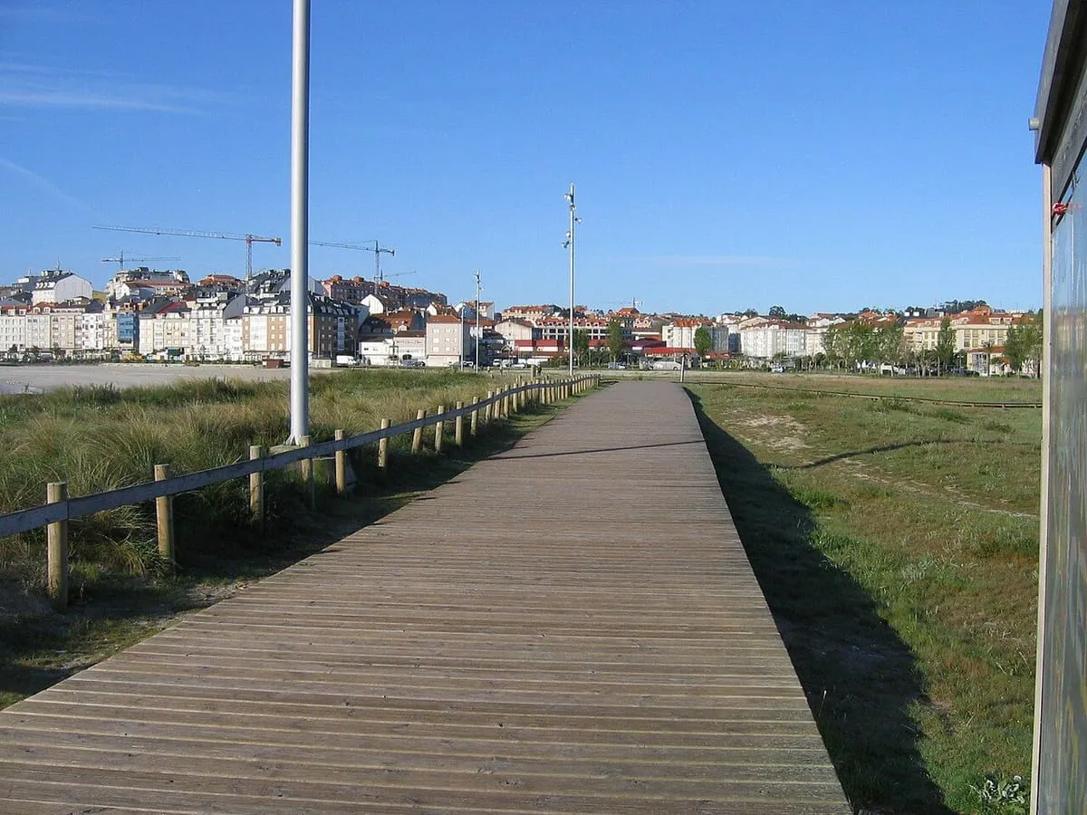 Paseo de madera junto a la playa de Baltar, con las casas de Portonovo al fondo