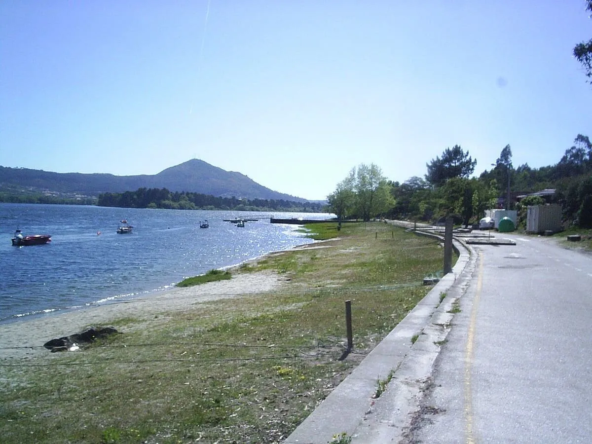 Playa fluvial de Goián junto al Miño, con barcas en el agua y un monte al fondo