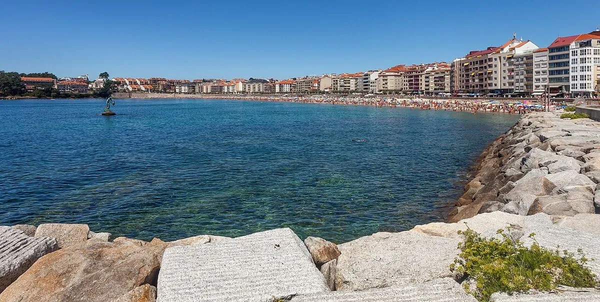 Aguas claras de la playa de Silgar, con el paseo y los edificios de Sanxenxo al fondo