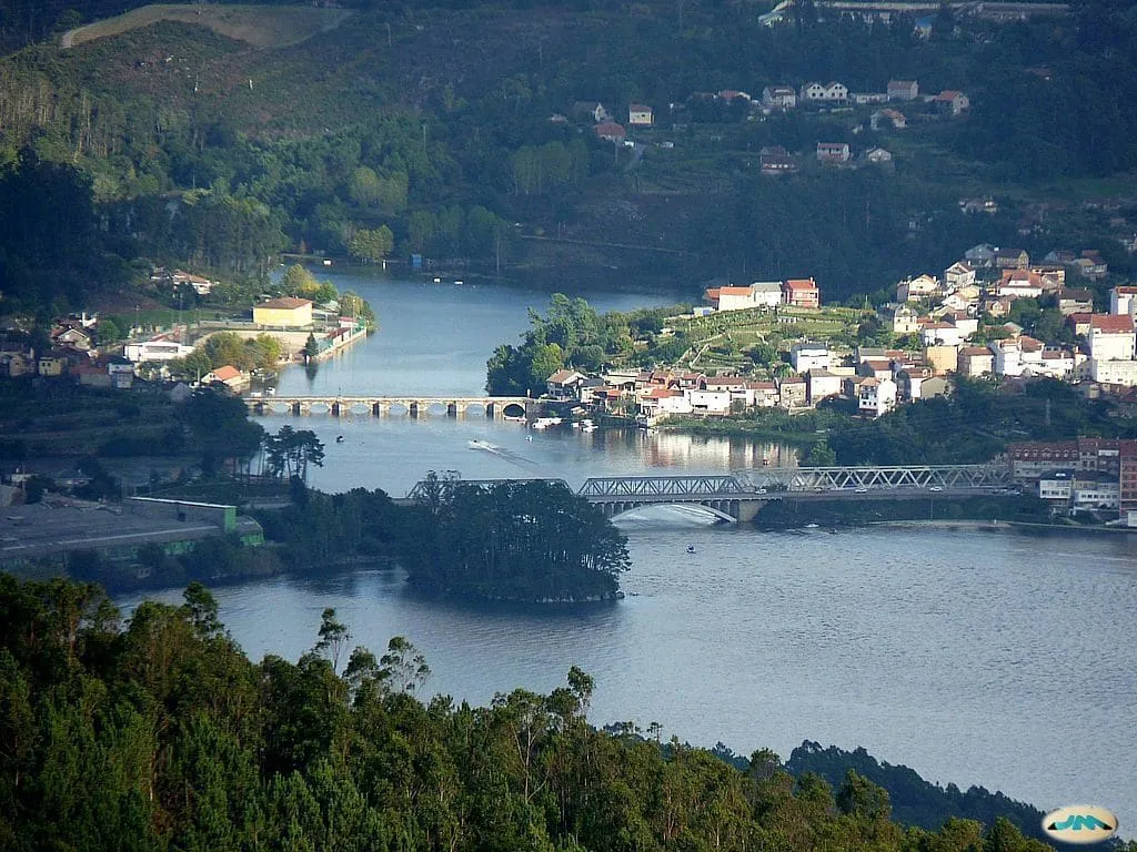 Vista desde lo alto del río Verdugo con el puente medieval y un puente de hierro, y las casas de Ponte Sampaio