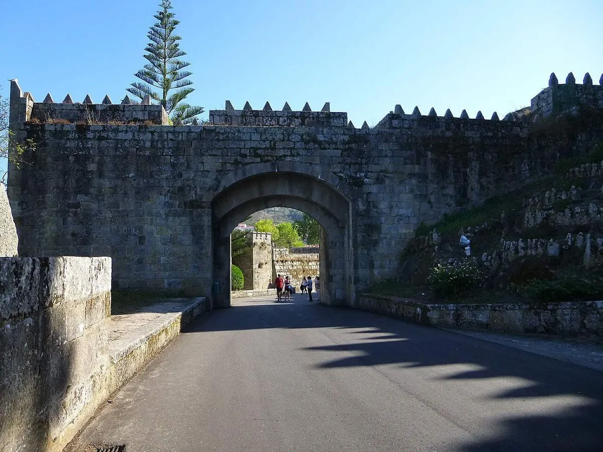 Arco de piedra en la muralla de Monterreal, con la carretera que entra a la península de Monte Boi