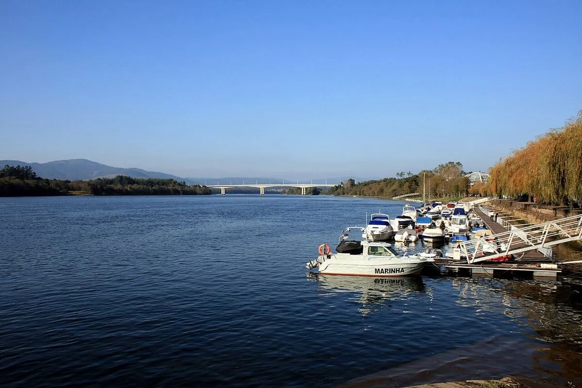 Embarcaciones amarradas en el pantalán del Miño en Vila Nova de Cerveira, con un puente al fondo