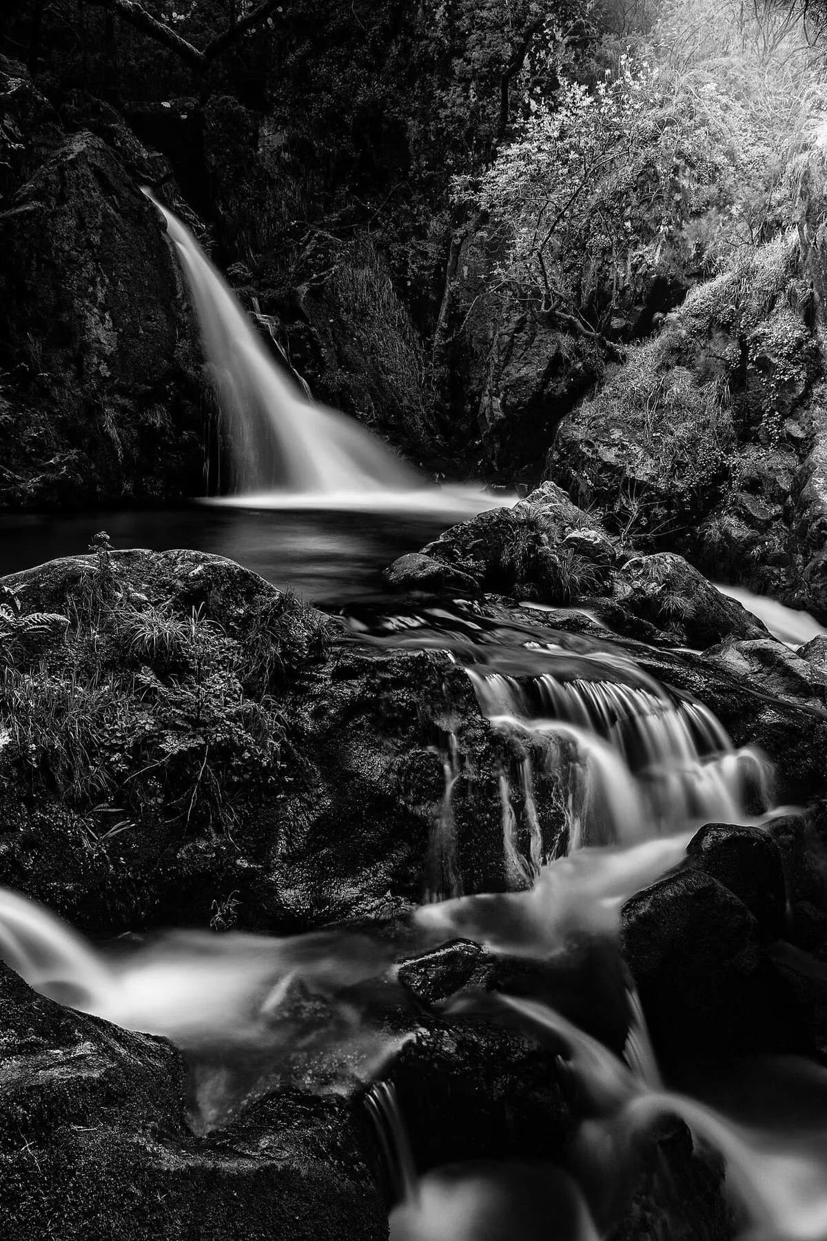 Salto de agua entre rocas oscuras en las fervenzas de Raxoi, en blanco y negro
