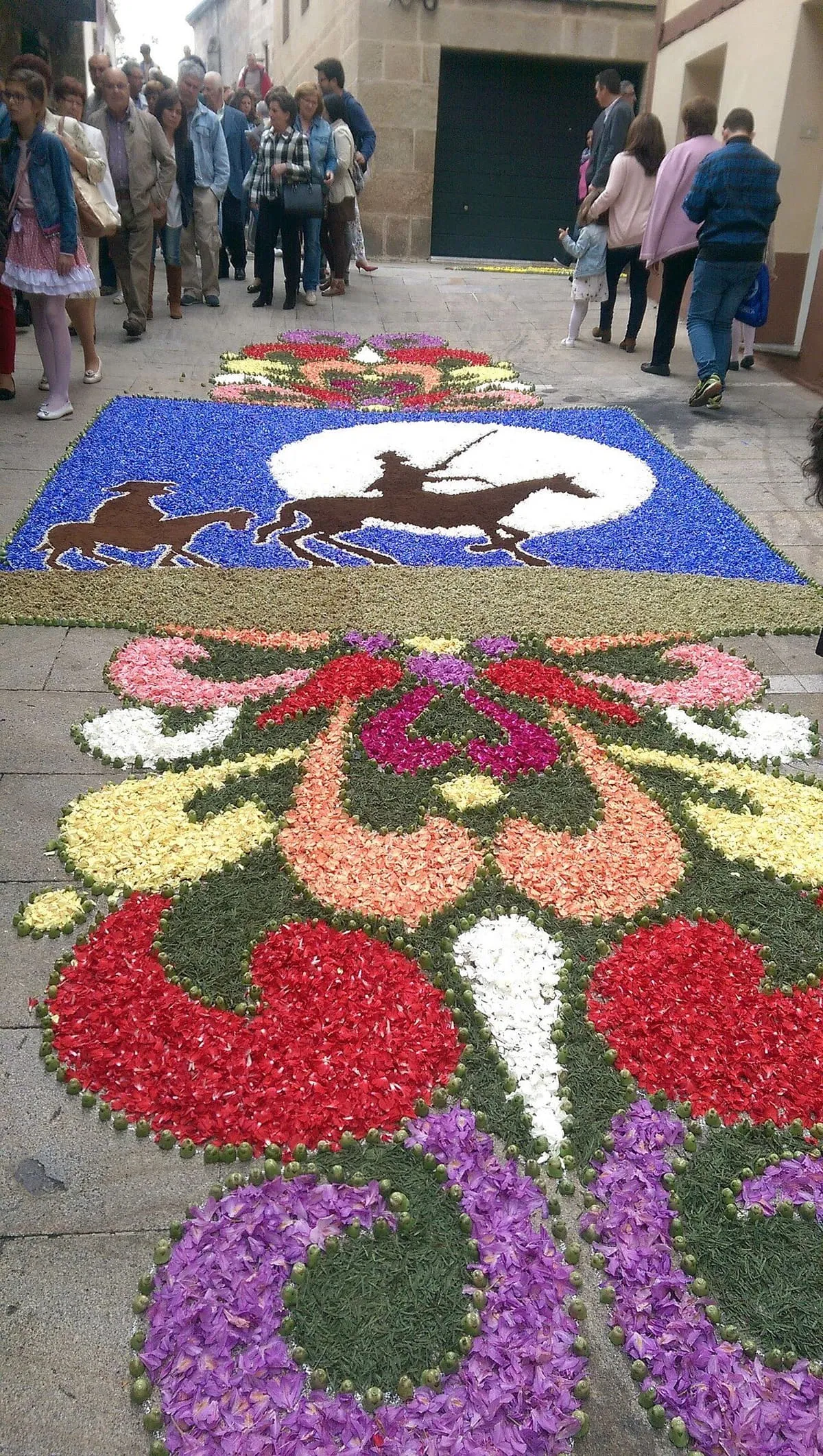 Detalle de una alfombra floral de la Festa da Coca con flores de colores y dos caballos en la parte superior