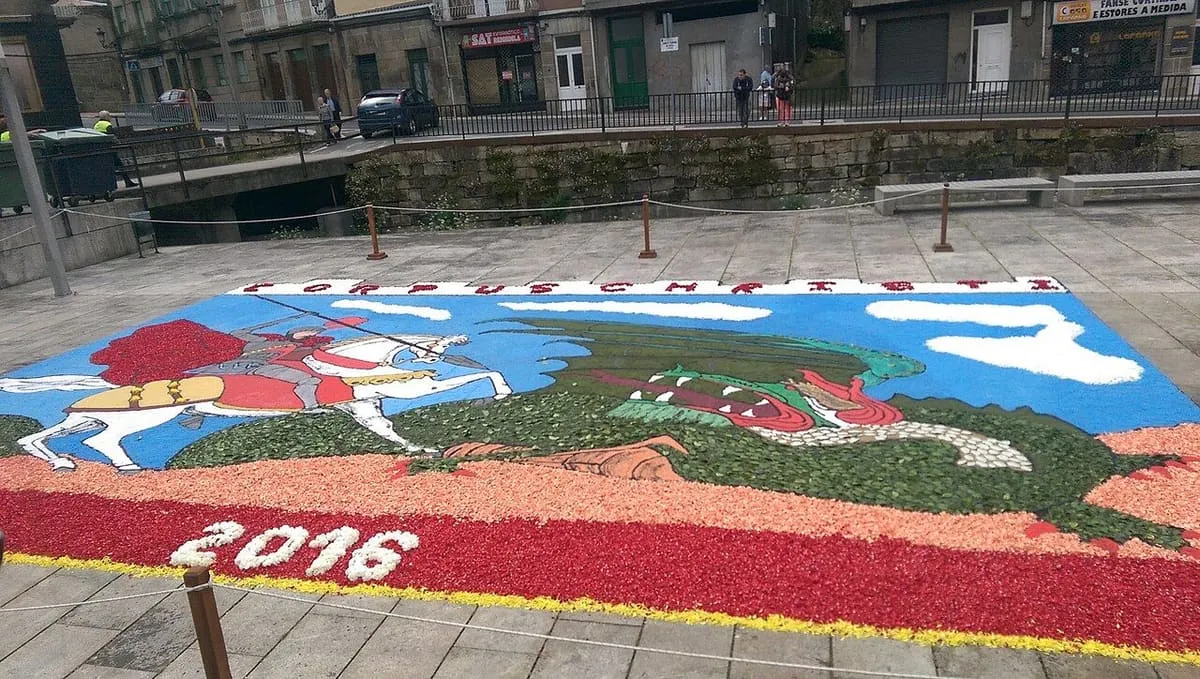 Alfombra floral de 2016 en el suelo de la plaza junto a la Casa da Torre, con un caballero y un dragón