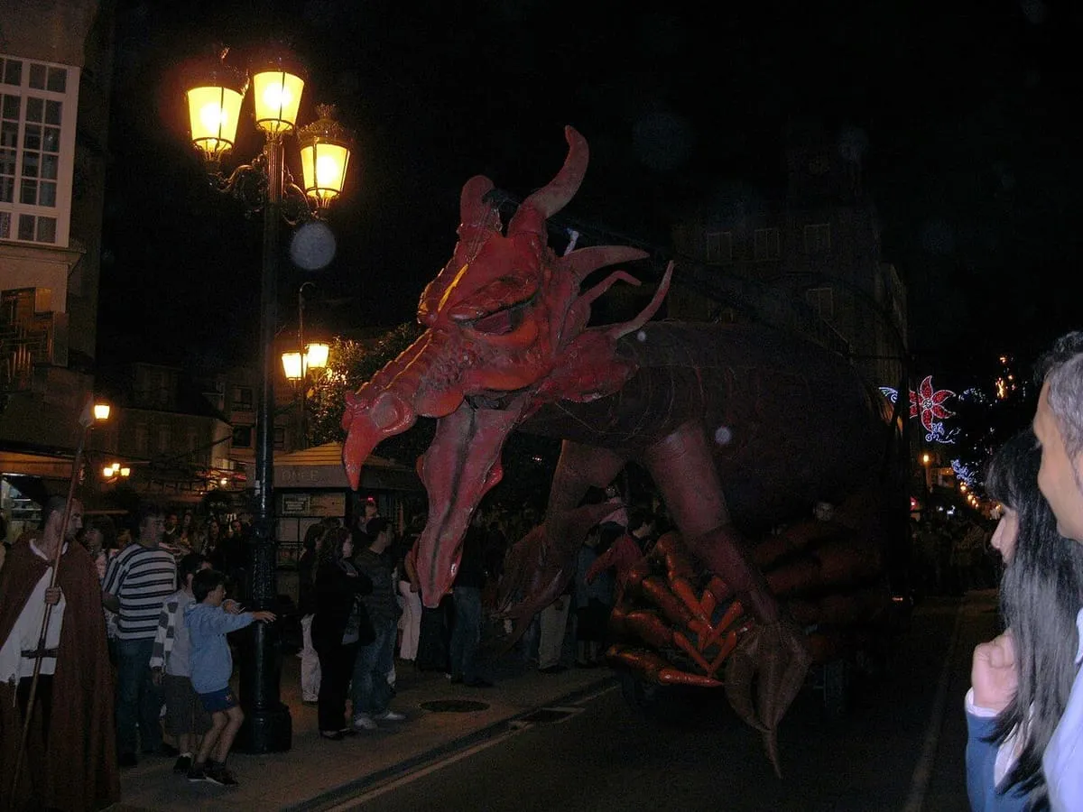 El dragón de la Coca recorriendo de noche una calle de Redondela entre el público