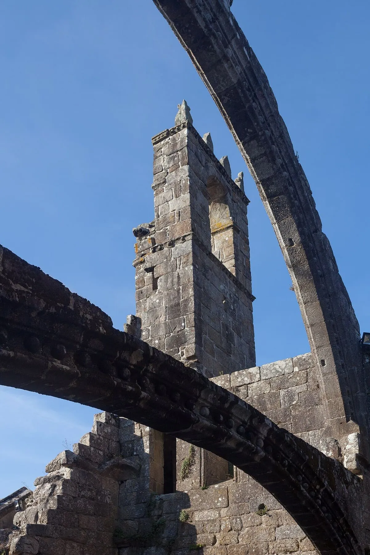 Espadaña de las ruinas vista a través de un arco apuntado de Santa Mariña Dozo