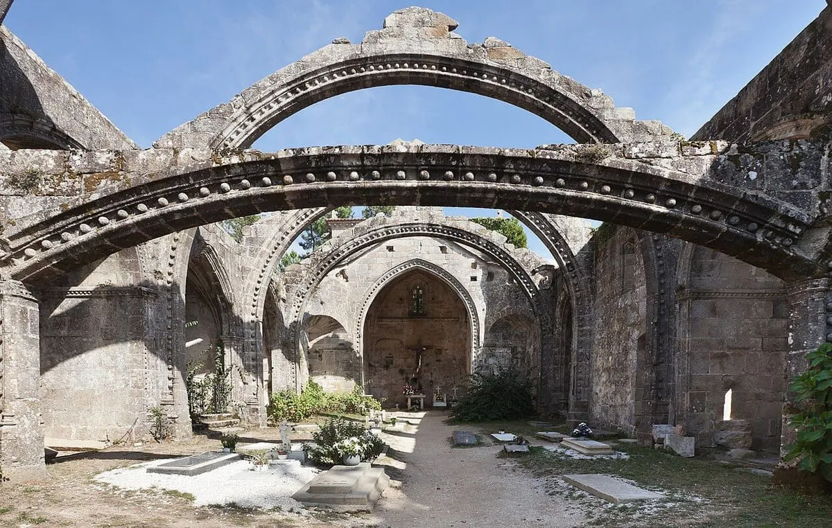 Interior sin techo de las ruinas de Santa Mariña Dozo, con arcos de granito y tumbas en el suelo