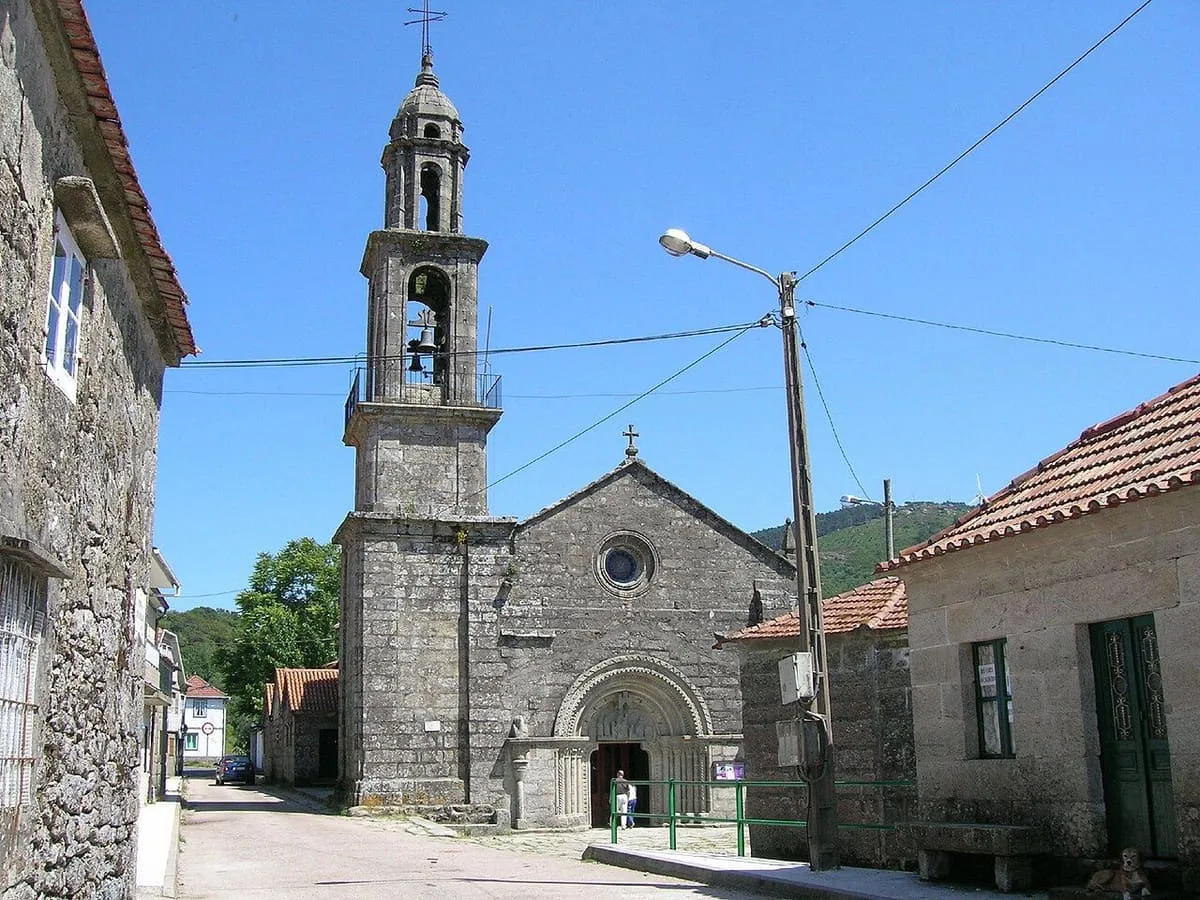 Iglesia de piedra con espadaña del santuario de A Franqueira, entre casas de aldea