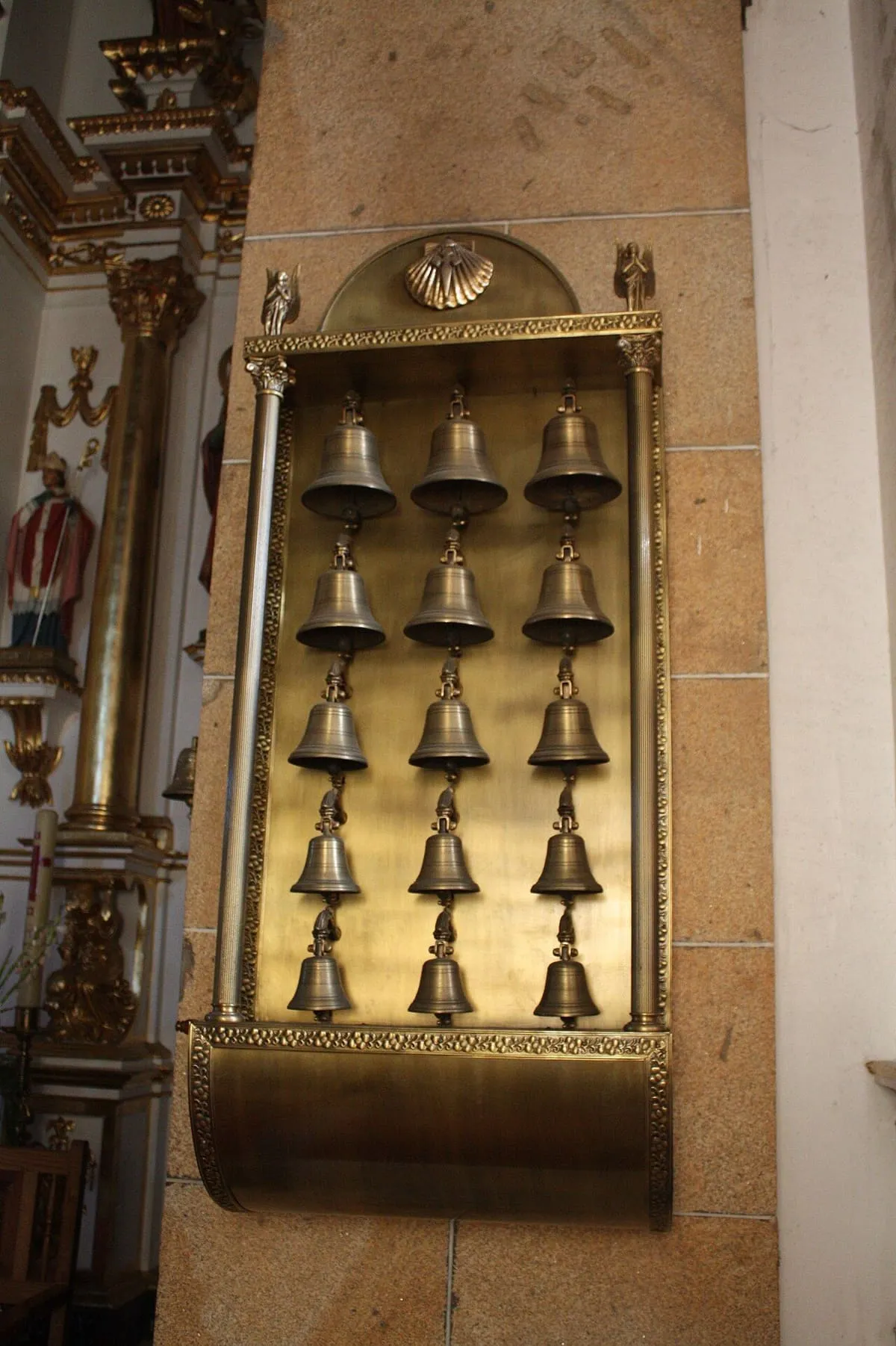 Una hilera de campanillas de bronce colgadas en un retablo del santuario