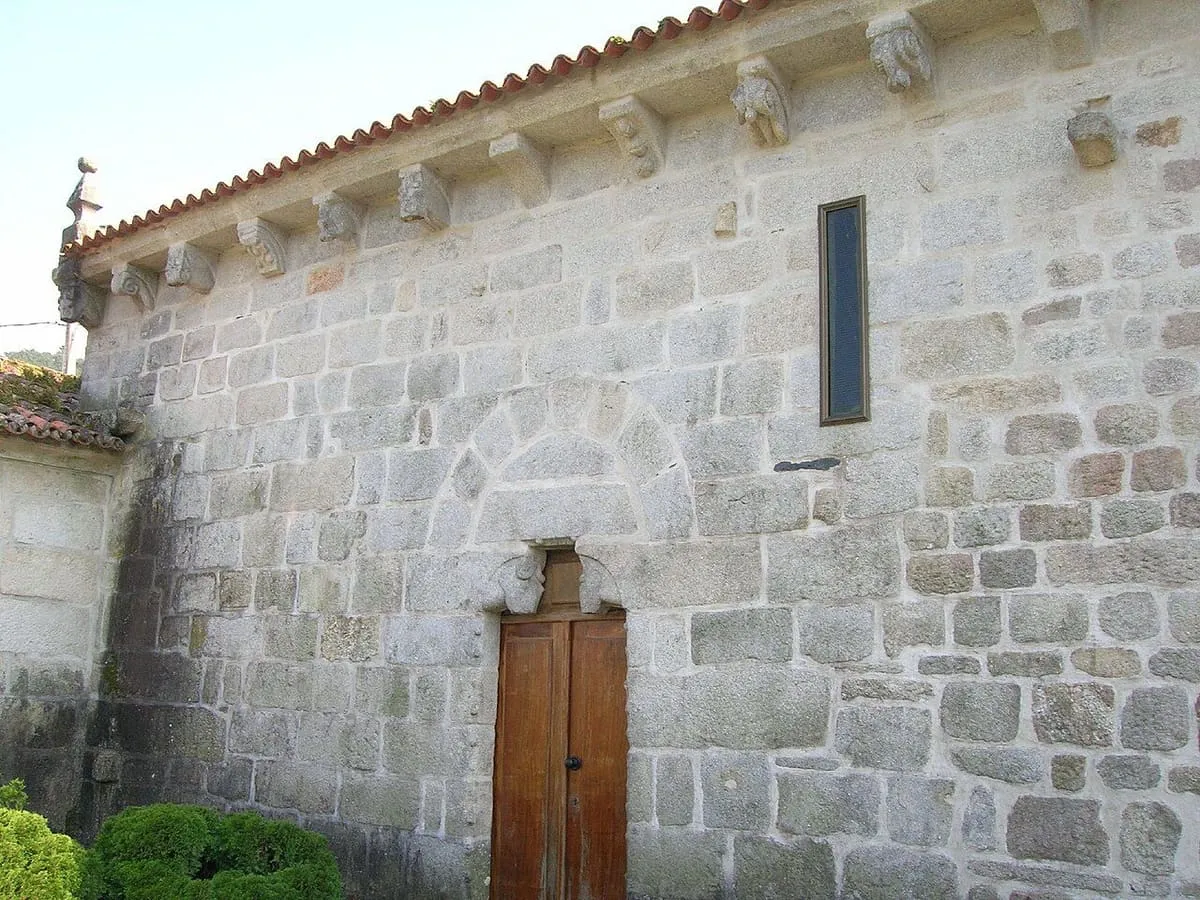 El muro lateral de sillería de la iglesia de San Salvador de Tebra con una pequeña puerta de madera