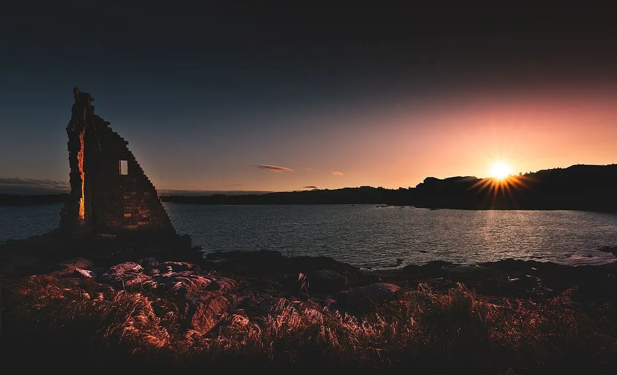 Silueta de la torre a contraluz mientras el sol se pone sobre la ría de Arousa