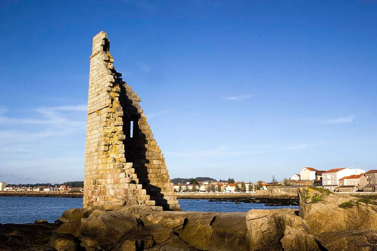 La torre de San Sadurniño sobre las rocas, con las casas de San Tomé do Mar al fondo