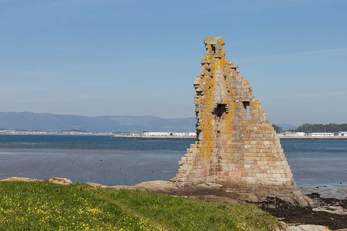 La torre en ruinas sobre las rocas, con la ría de Arousa y la costa al fondo