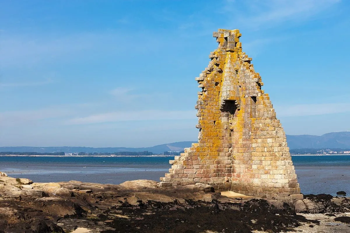 Los muros de la torre de San Sadurniño levantados sobre las rocas, junto al agua