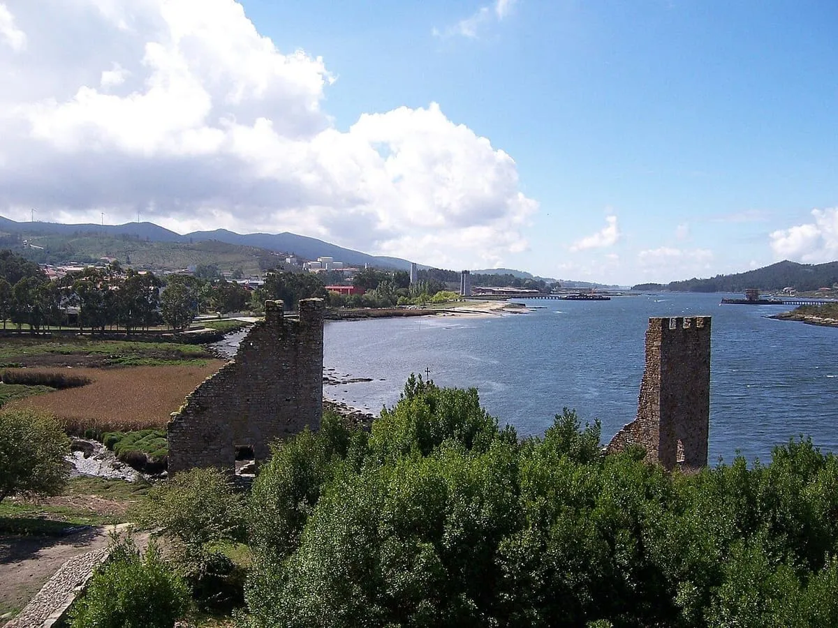 Las dos torres a orillas del Ulla, con el agua del río y los montes de la ría de Arousa al fondo