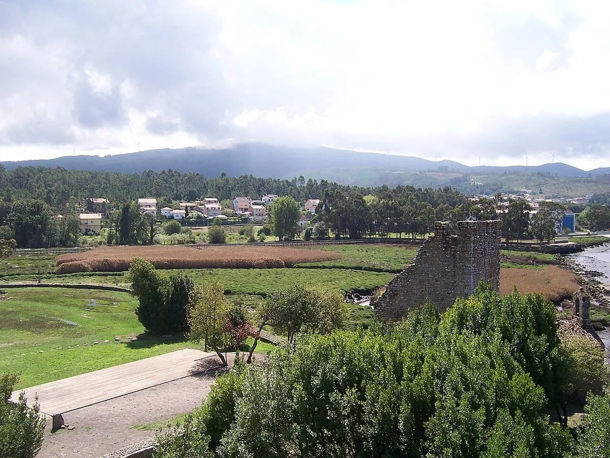 Una de las torres entre la vegetación, con las marismas del Ulla y las casas de Catoira al fondo