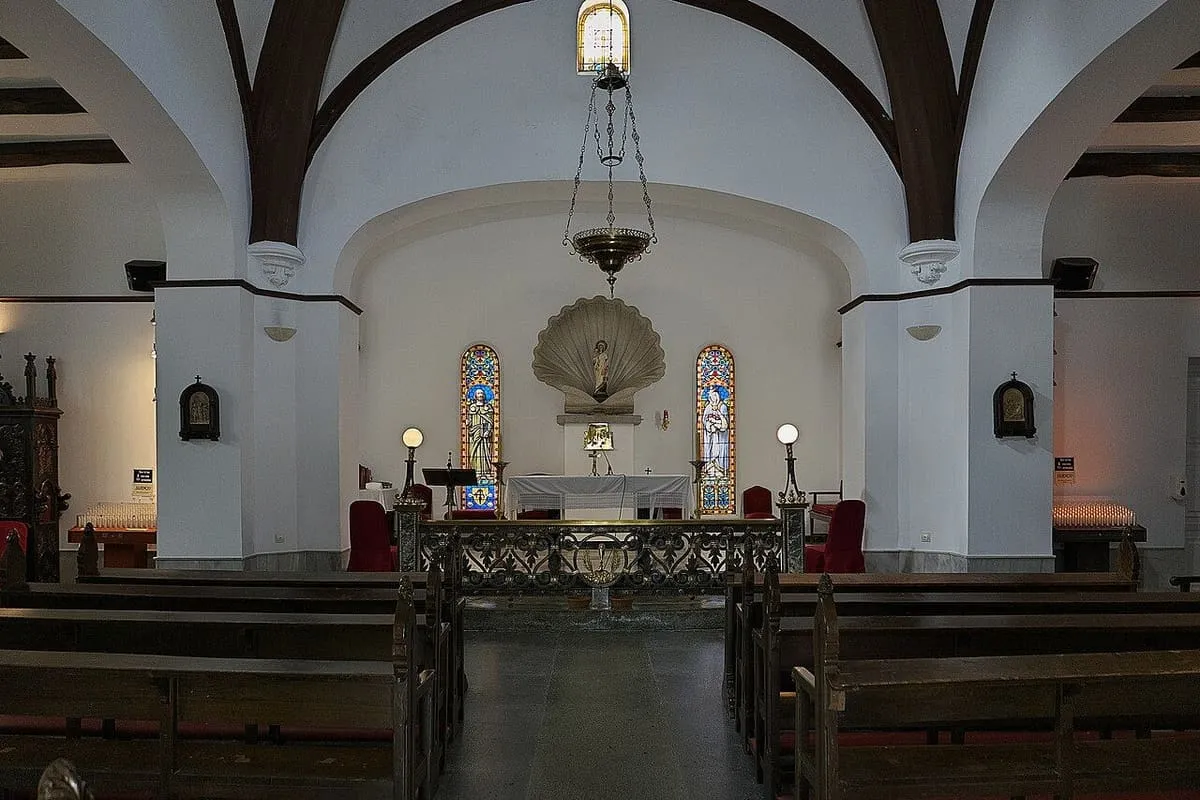 Interior blanco de la capilla de San Caralampio, con el altar y una vieira sobre él