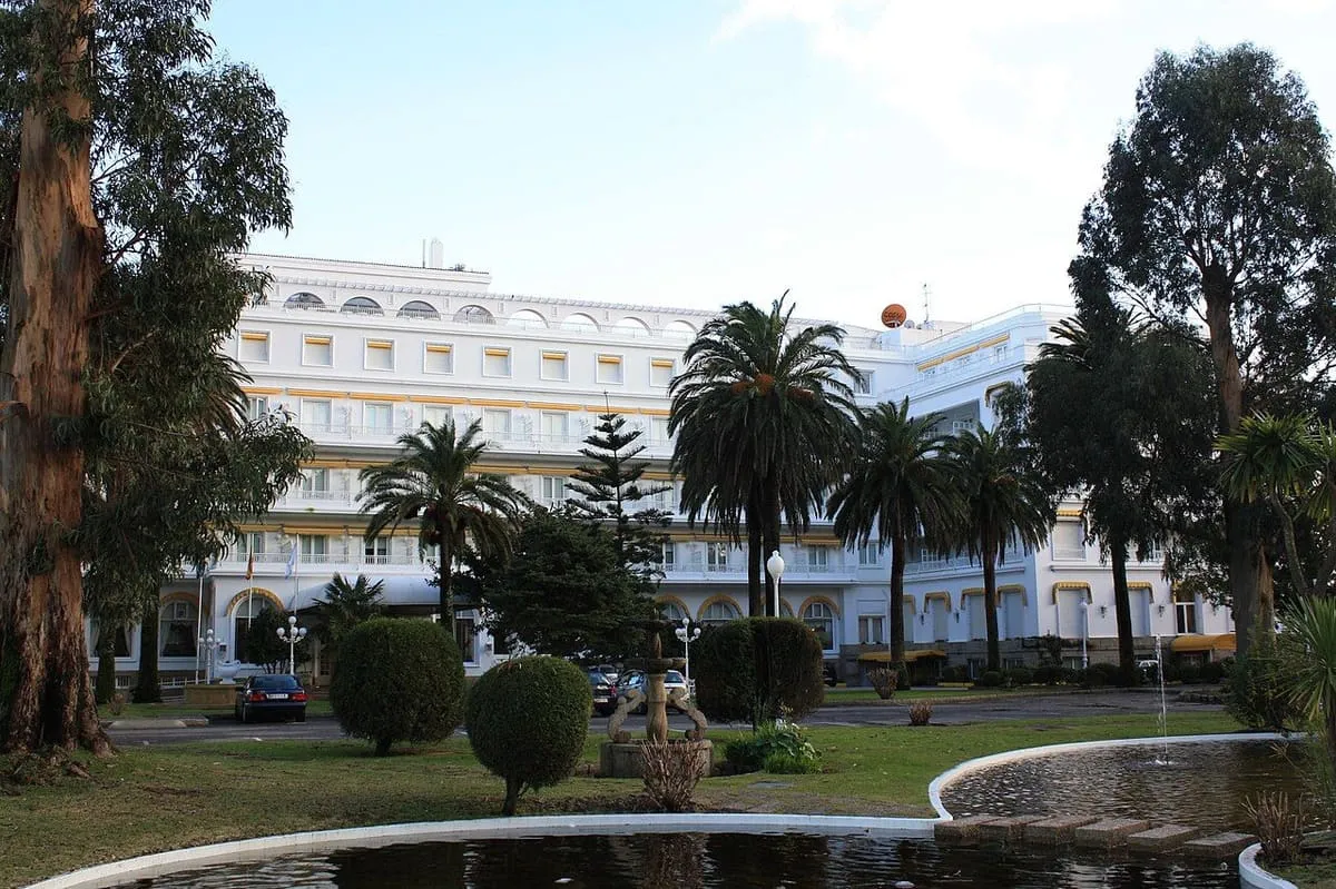 Fachada blanca del Gran Hotel de A Toxa entre palmeras y pinos