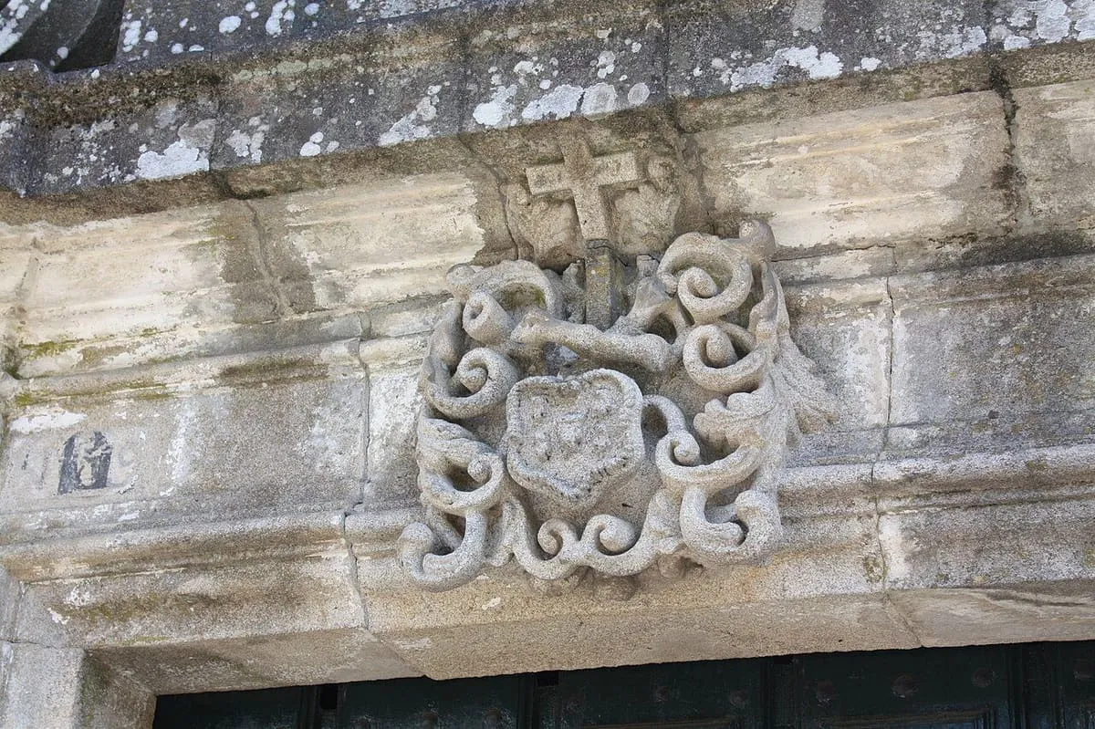Un escudo con cruz y adornos de piedra sobre un dintel del convento de las Clarisas