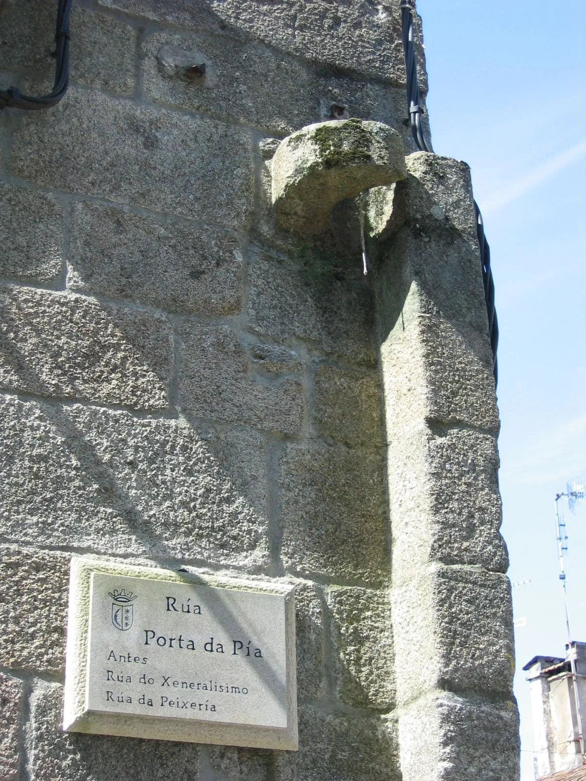 Muro de piedra con la placa de la rúa Porta da Pía, en Tui