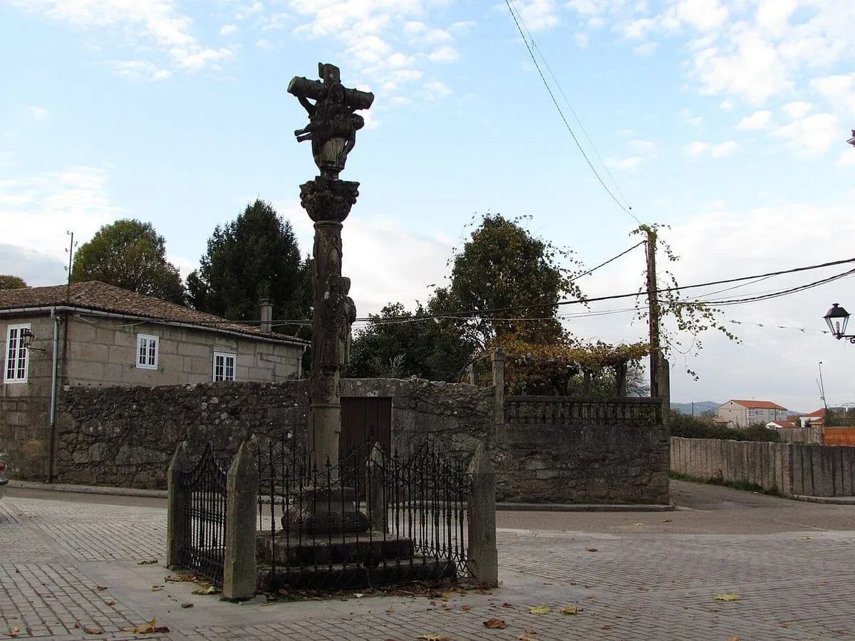 El cruceiro de San Bartolomeu, alto y rodeado de una verja, en la plaza de Rebordáns