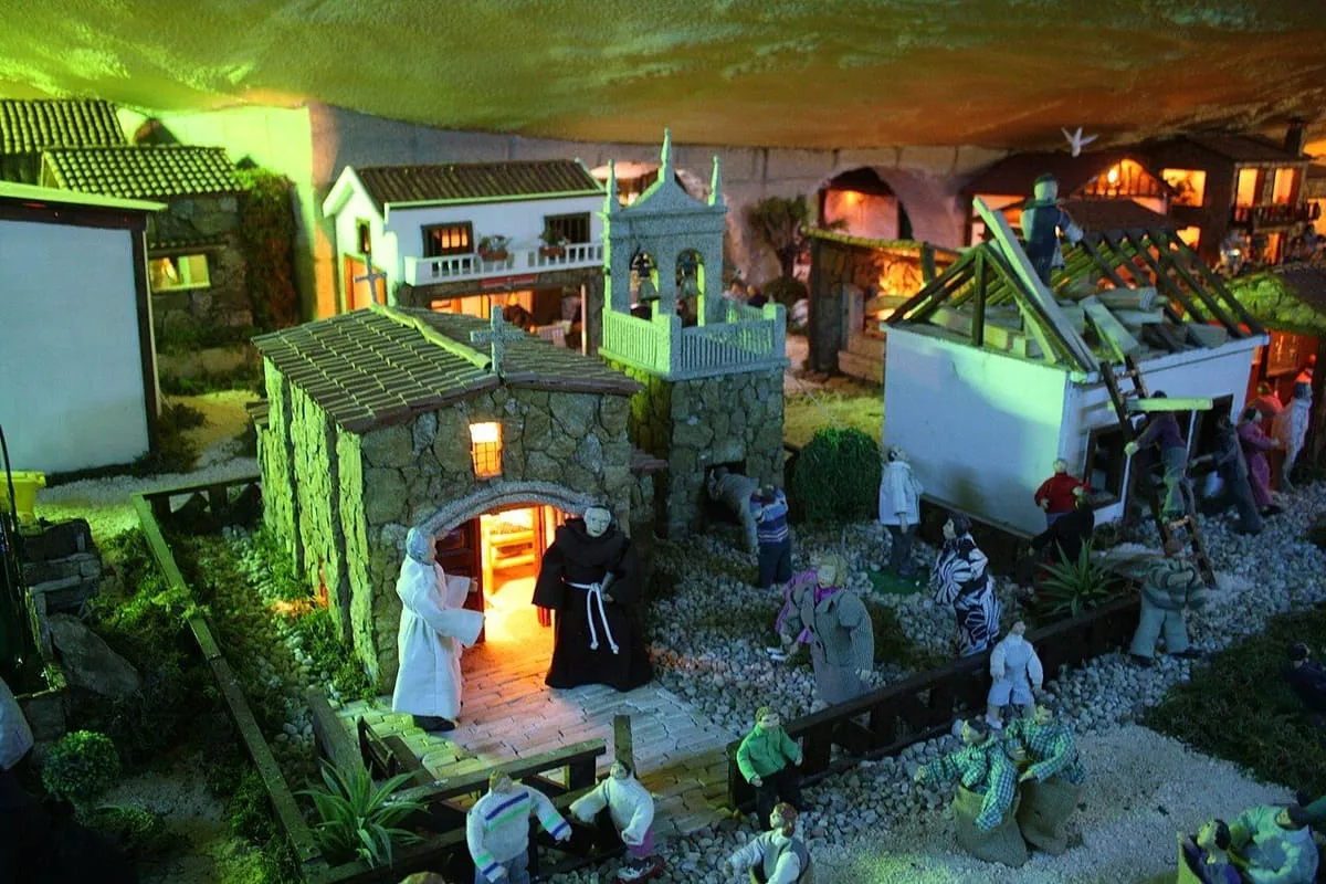 Casas de piedra con iglesia y campanario en miniatura, iluminadas, en el Belén de Valga