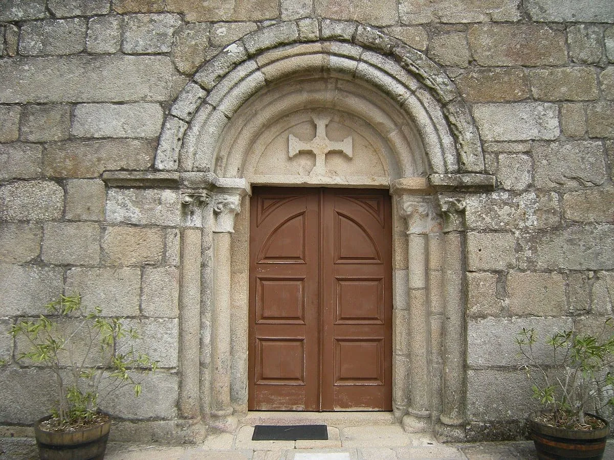 Portada románica de arco de medio punto con una cruz sobre la puerta, en Santa Cristina de Campaña