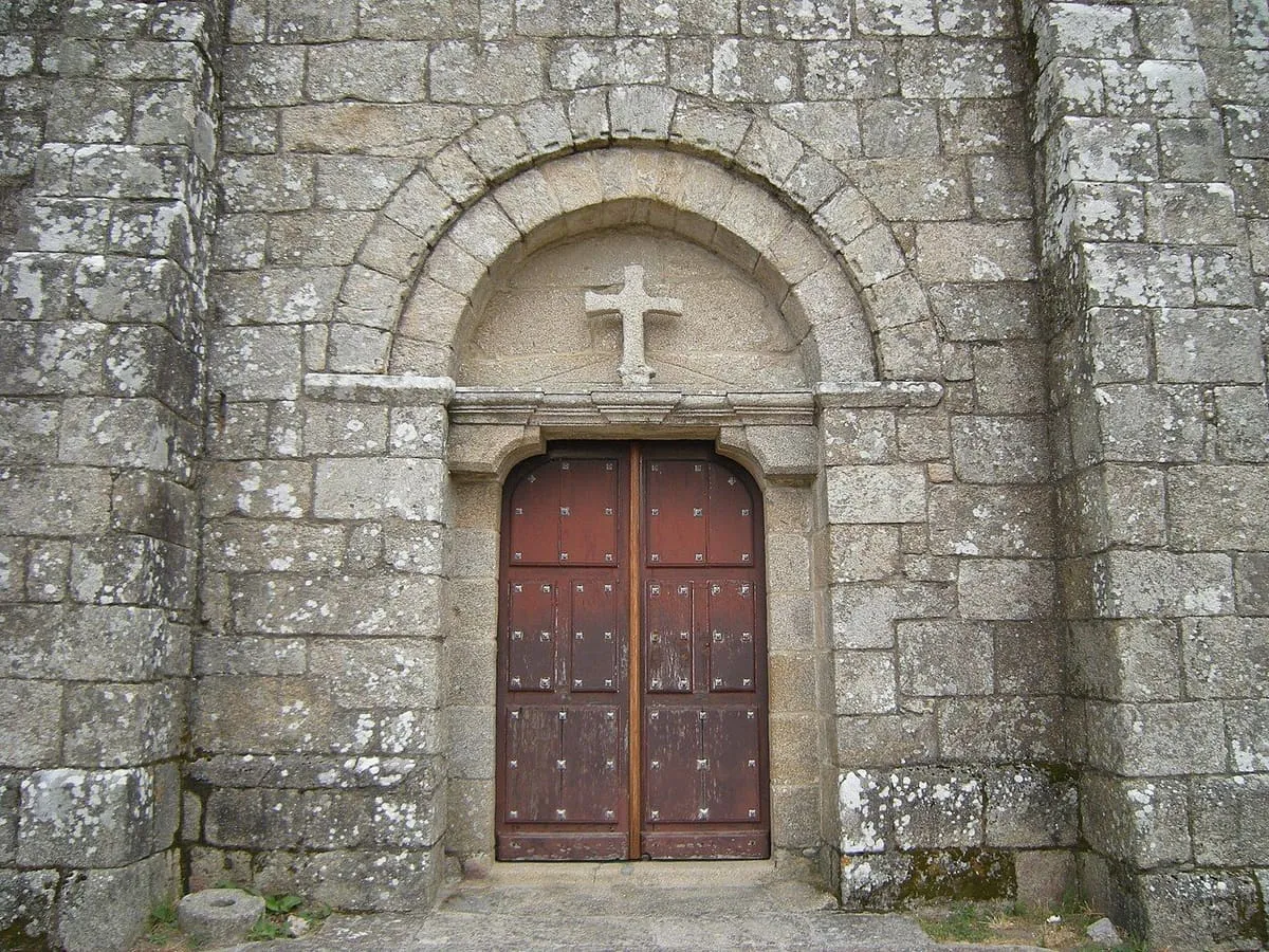 Portada de arco de medio punto con una cruz en el tímpano, en Santa María de Xanza
