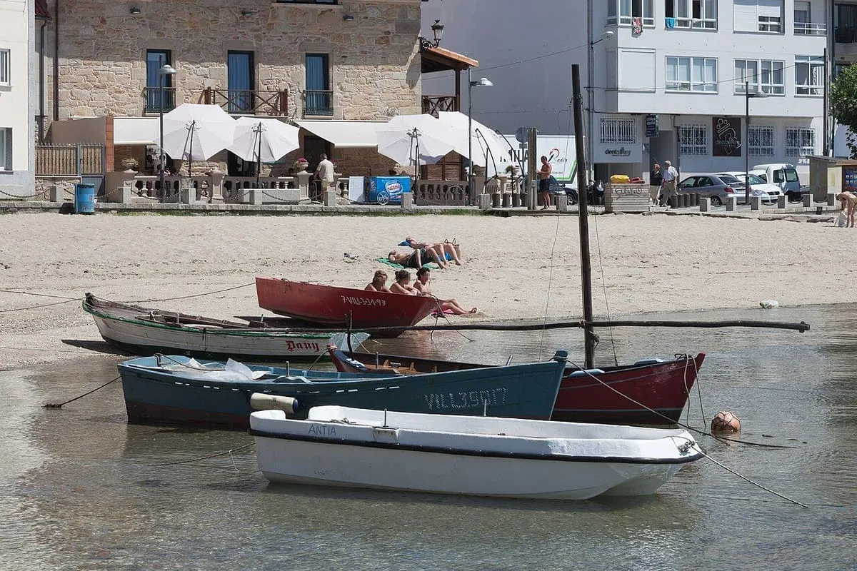 Botes de madera varados sobre la arena de la playa de Portugalete, con casas al fondo