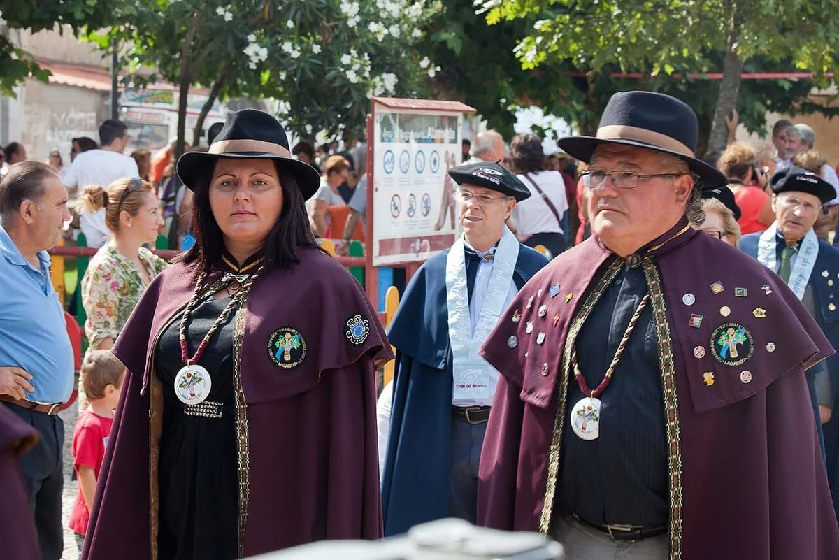Cofrades de la Orde da Ameixa con capas y sombreros oscuros durante la fiesta de la almeja