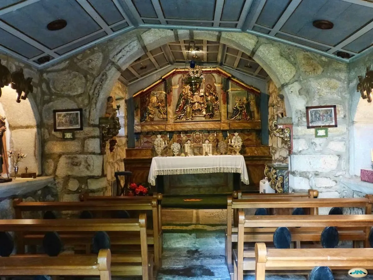 Interior de la capilla del pazo de Rubiáns, con un retablo de madera policromada y bancos