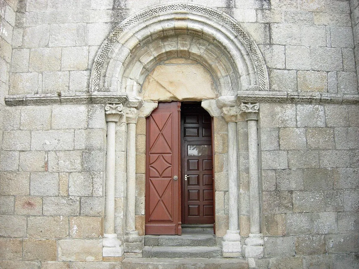 Portada románica de arcos de medio punto sobre columnas, con la puerta de madera abierta