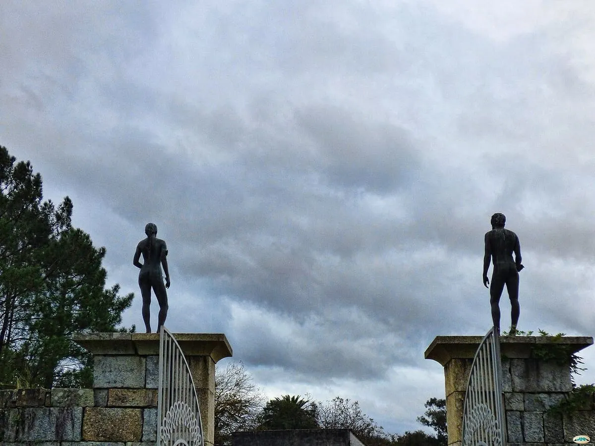 Dos estatuas de figuras desnudas sobre pilares, a la entrada de la finca