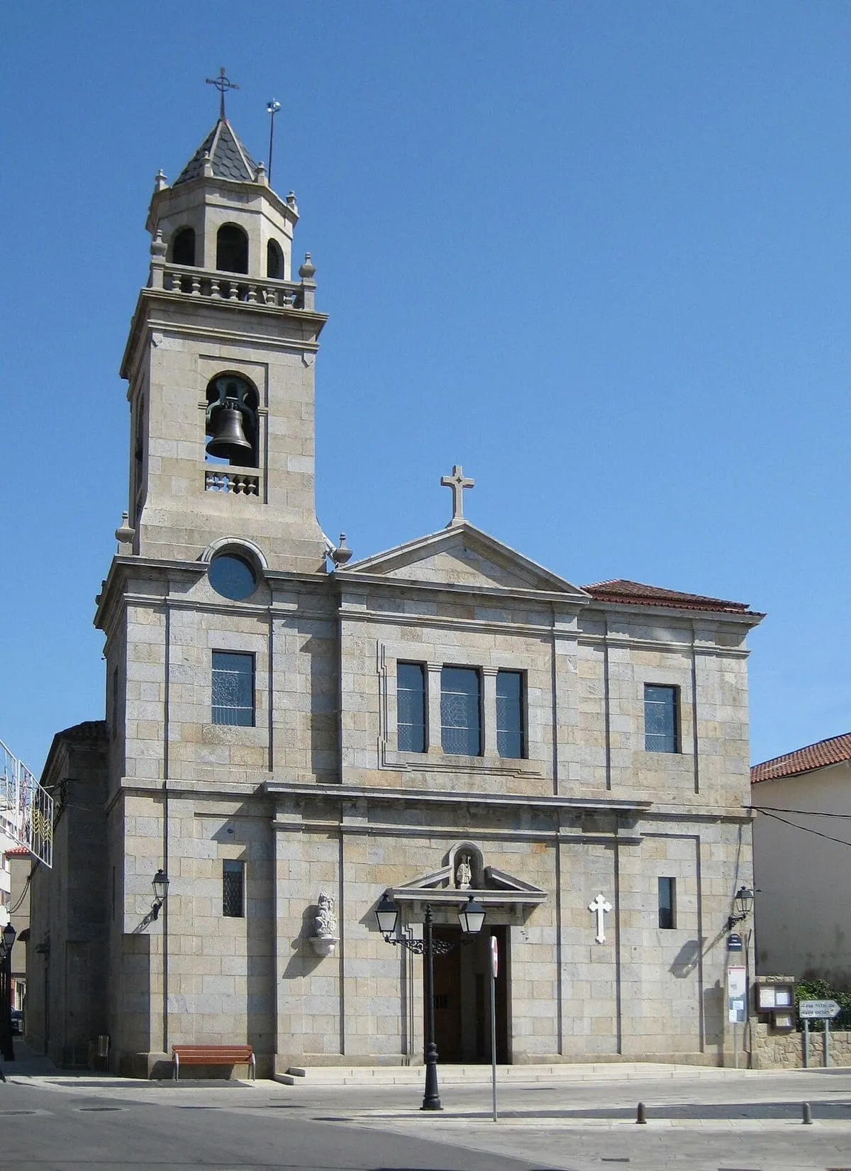 Iglesia de piedra con campanario y fachada clara en Vilanova de Arousa
