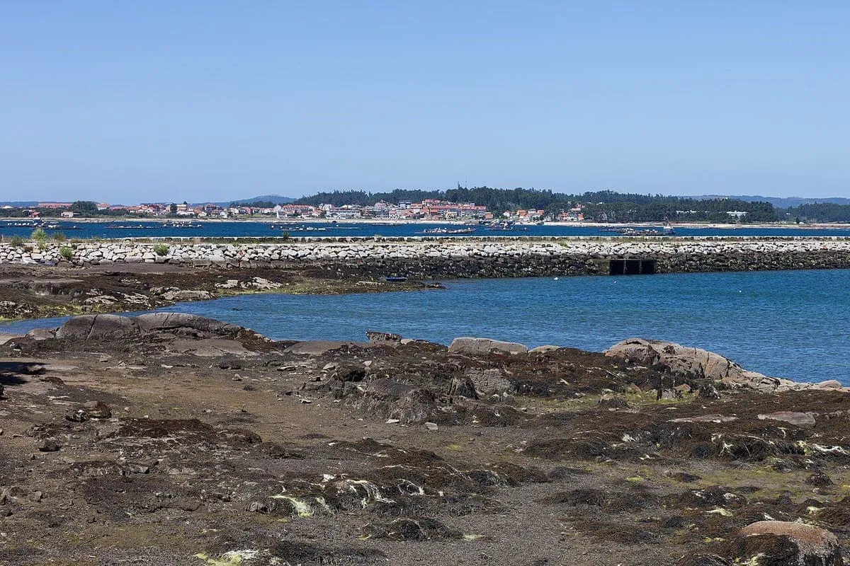 Rocas y espigón del puerto de Vilanova de Arousa con la ría al fondo