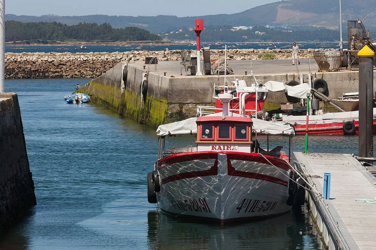 Barco pesquero rojo y blanco amarrado en un pantalán del puerto