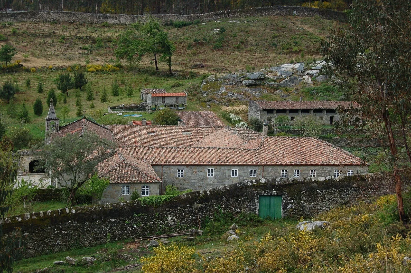 El convento de San Francisco de Louro, con sus tejados rojos entre prados y monte, al pie del monte Oroso