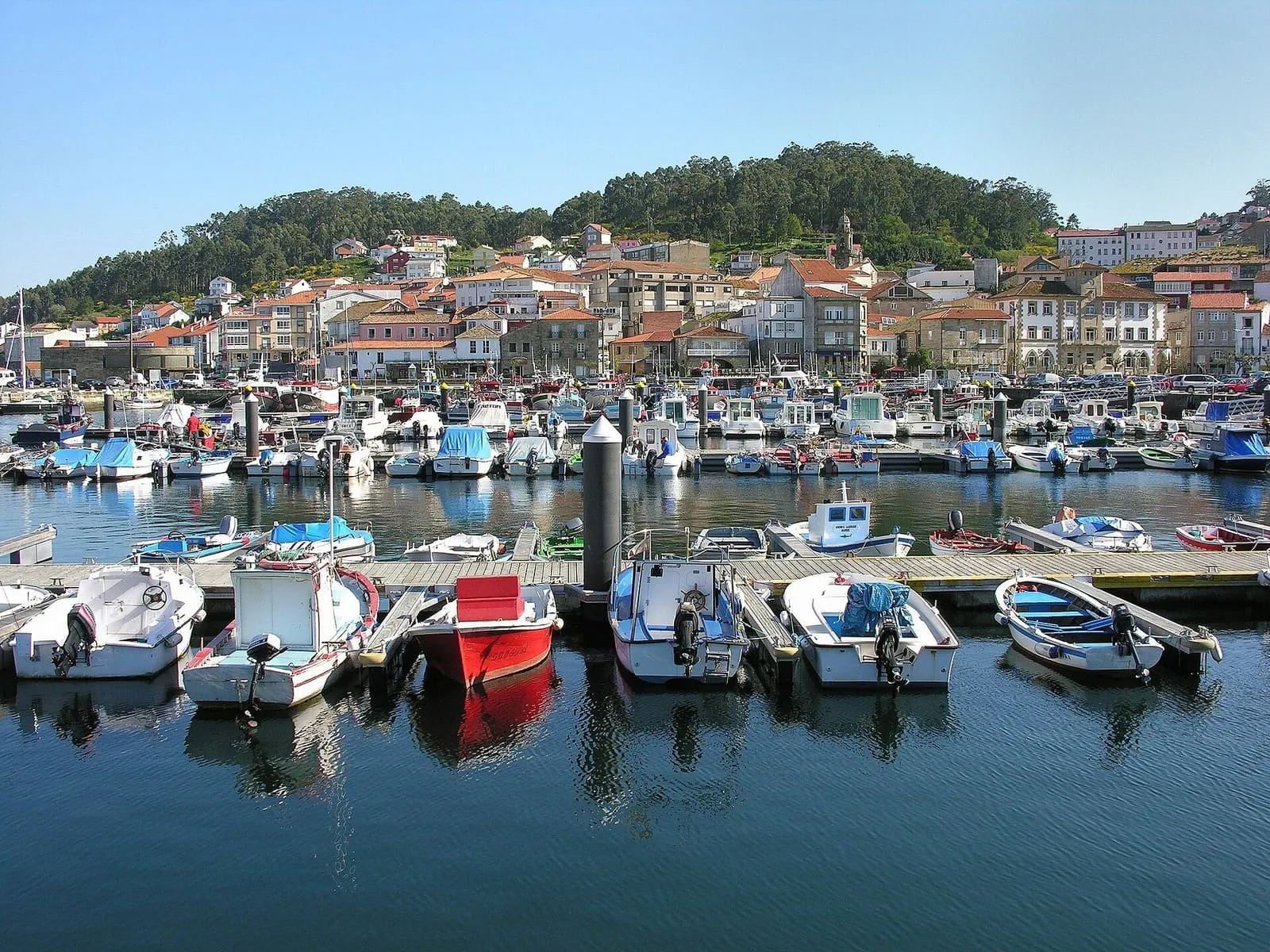 Puerto de Muros con barcas amarradas y las casas de la villa sobre la colina