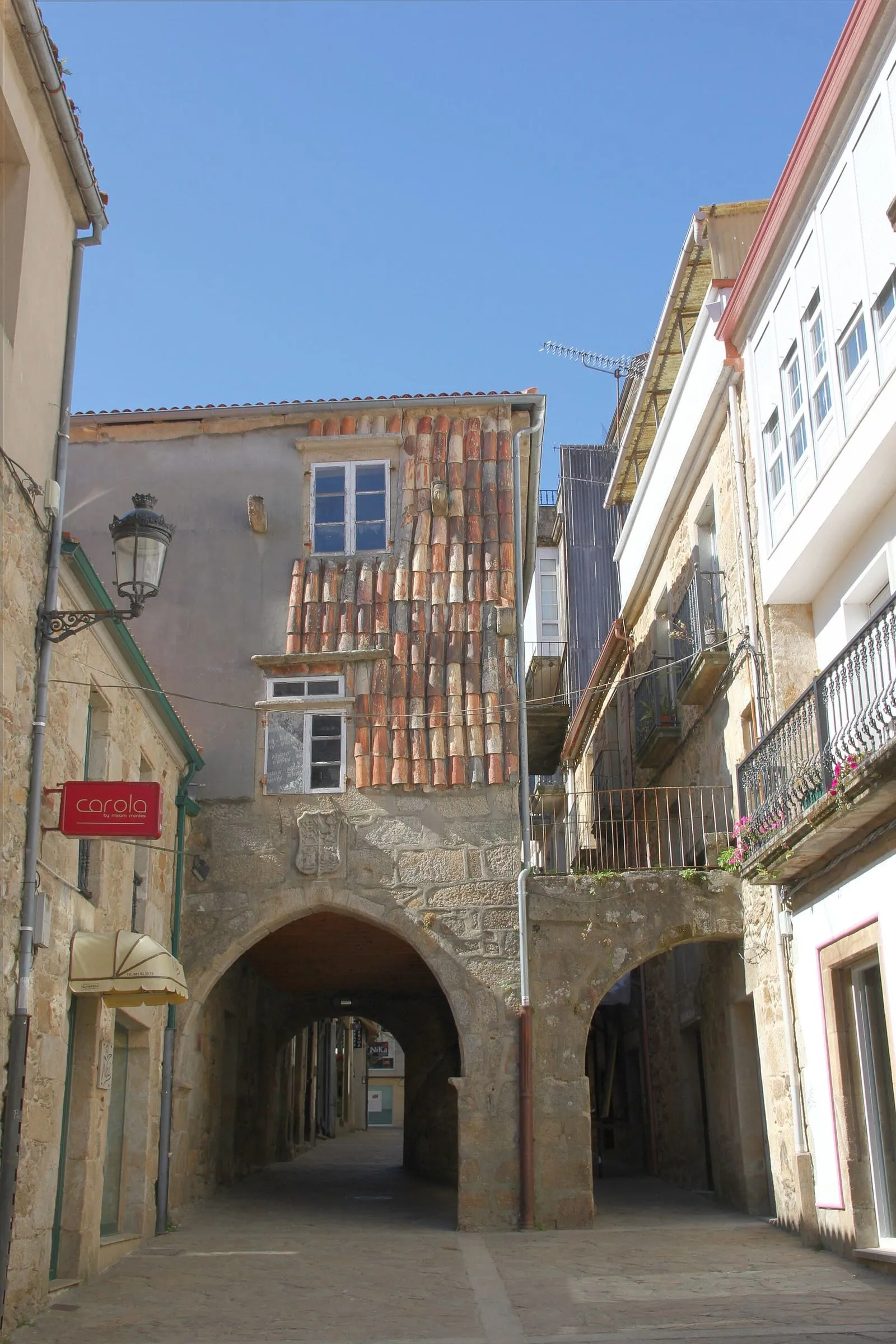 Calle del casco vello de Noia con un soportal de arcos y casas de piedra