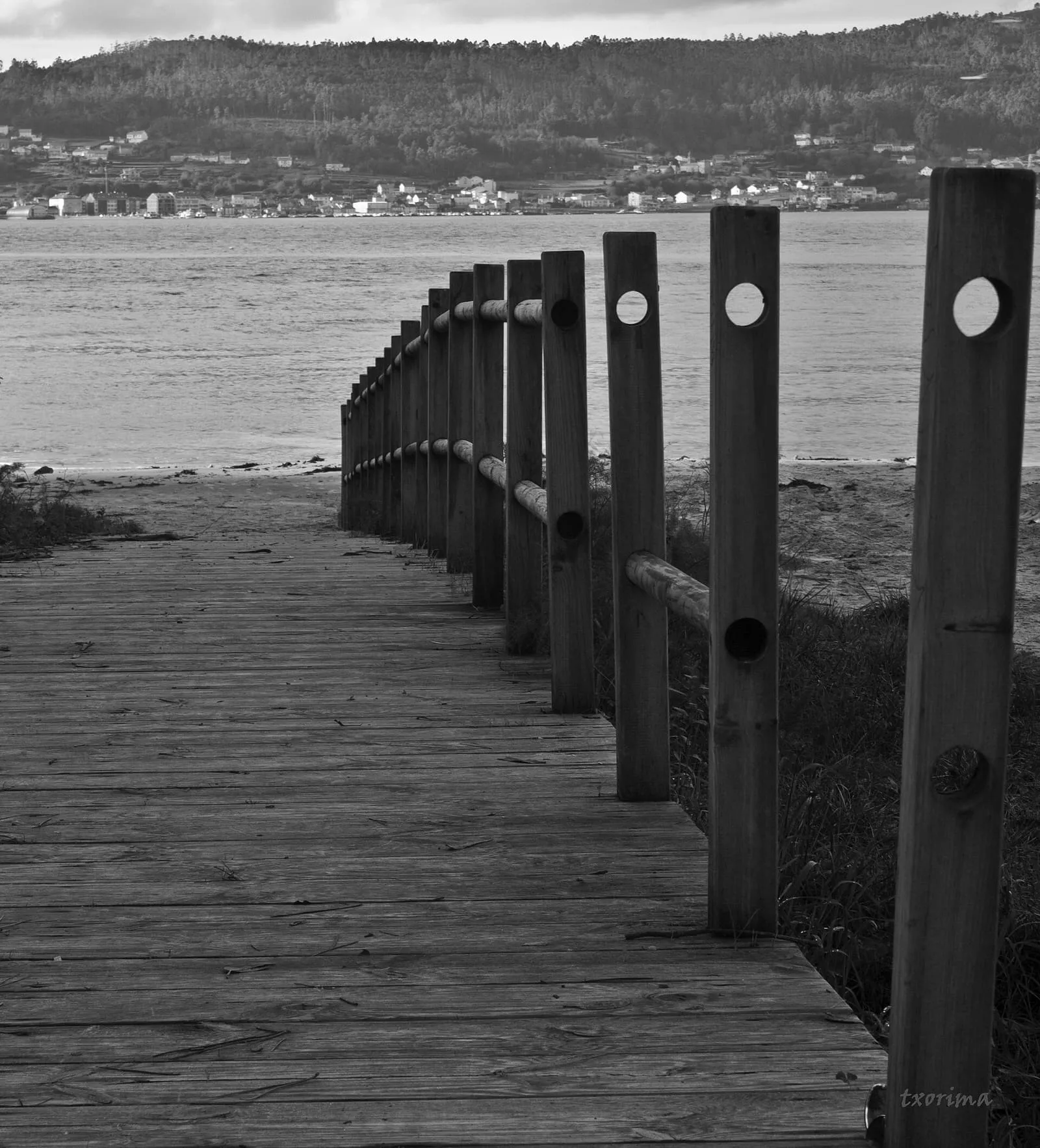 Pasarela de madera con postes que baja hacia la playa de Testal en blanco y negro