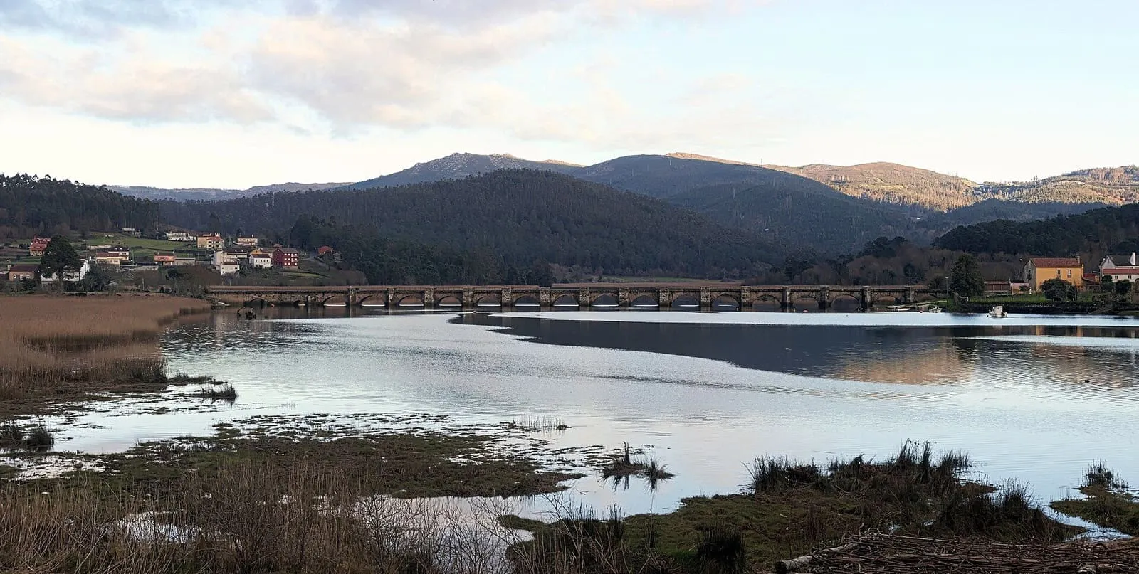 La larga ponte Nafonso de piedra cruzando la desembocadura del Tambre, con montes al fondo