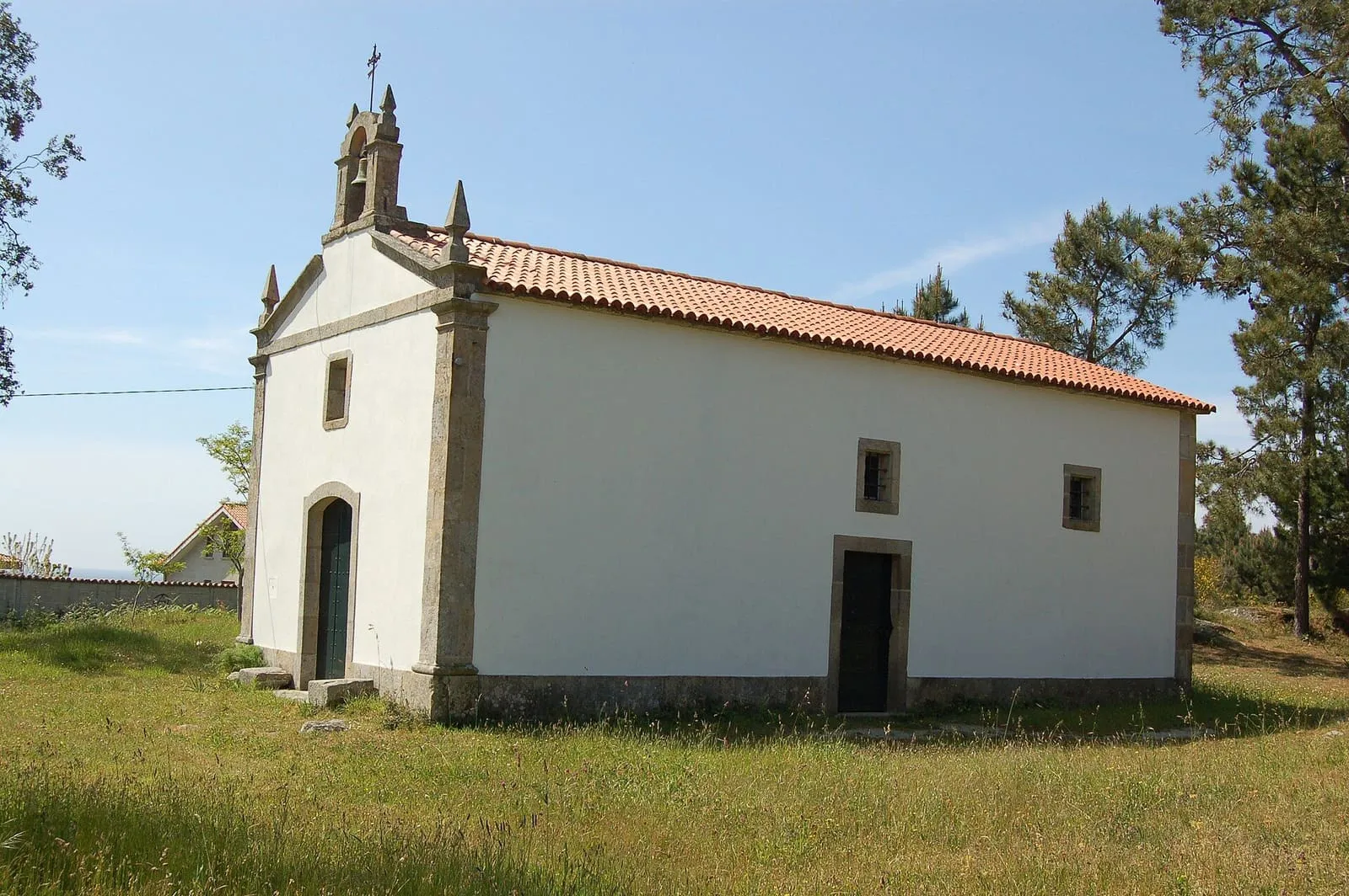 La ermida dos Desamparados o capilla de las Pardiñas, un edificio encalado con espadaña entre pinos
