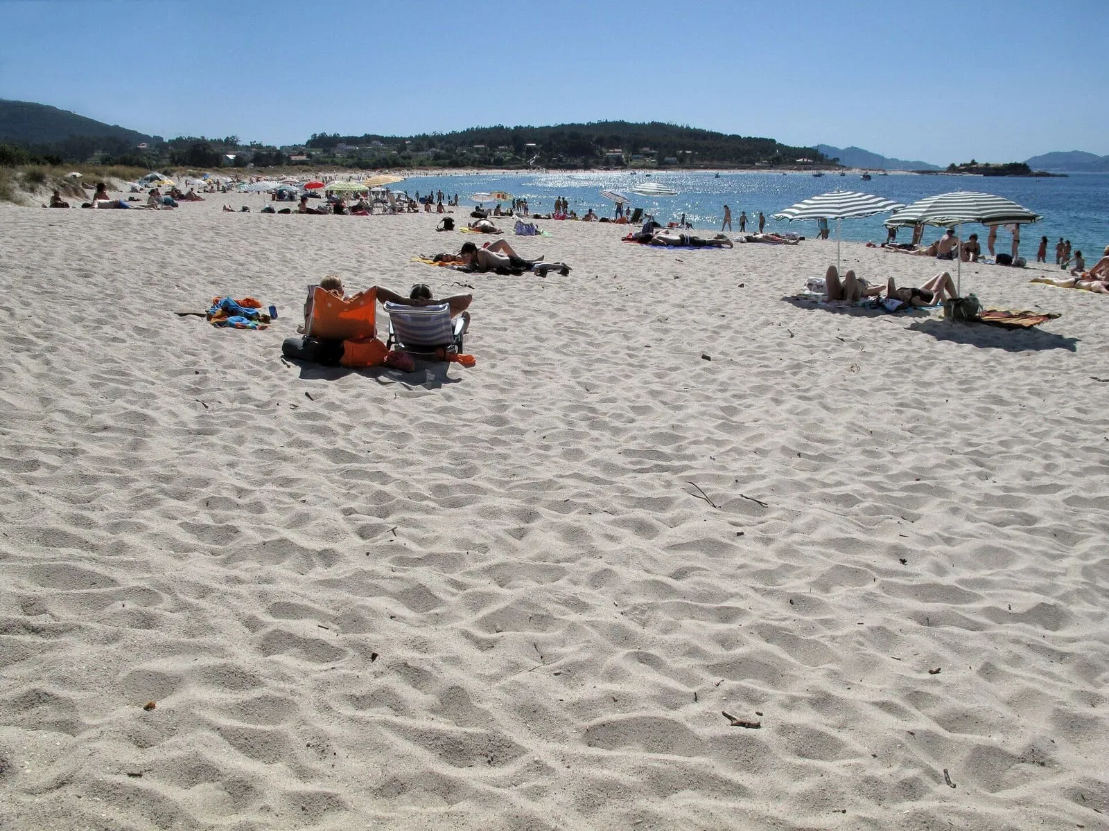 Arena blanca de la playa de Aguieira con bañistas y la ría al fondo